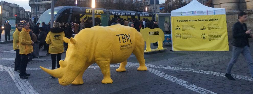Statue taille réelle de rhinocéros jaune devant une station de tramway dans les rues de Bordeaux.