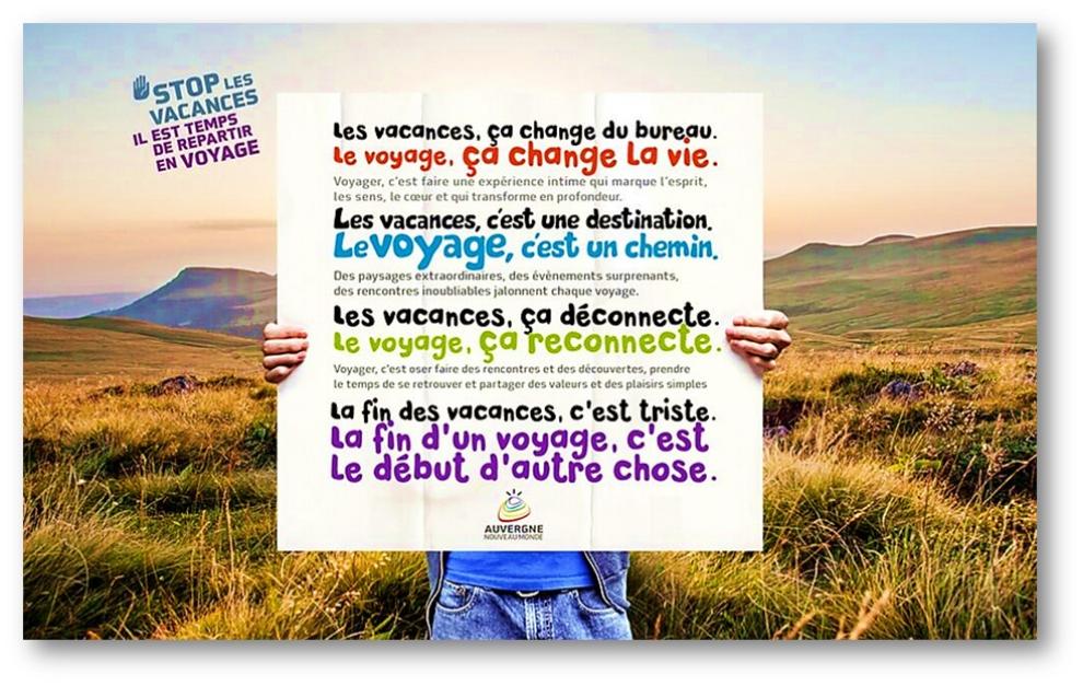 Texte publicitaire sur les bienfaits du voyage par rapports aux vacances sur une affiche tenue par quelqu'un sur fond de paysage d'Auvergne.